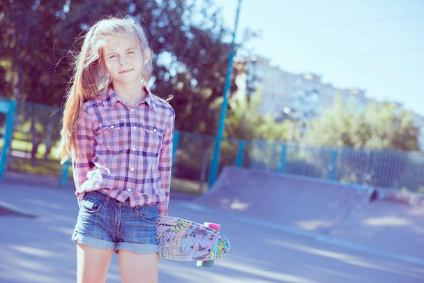 portrét dospívající dívky, stojící ve skateparku, držící skateboard v ruce - Fotografie, Obrázek