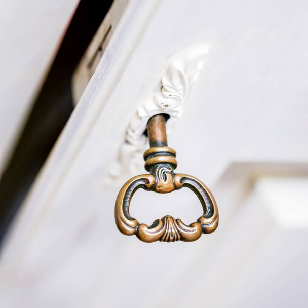Stary klucz w dziurce od klucza. Klucz w białych drewnianych drzwiach - Zdjęcie, obraz
