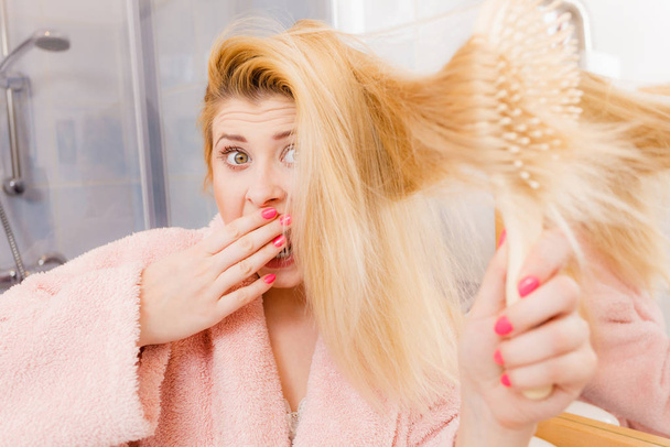 Shocked woman wearing dressing gown brushing her hair - Foto, Bild