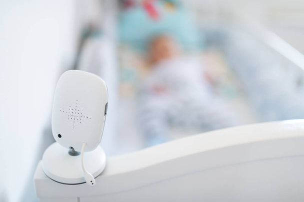 Close up of modern baby monitor on crib. In background is blurred baby boy. - Photo, Image