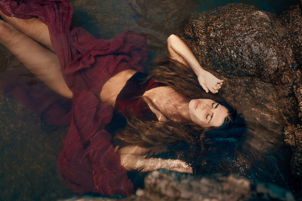 young attractive woman lying on rocks on sea beach - Fotografie, Obrázek
