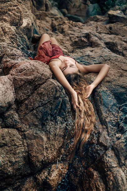 young attractive woman lying on rocks on sea beach - Zdjęcie, obraz