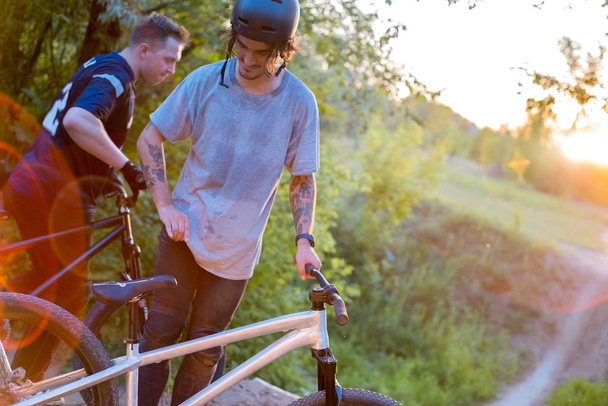 két biciklis-barát, kerékpárral, az erdőben, a lenyugvó nap ellen - Fotó, kép