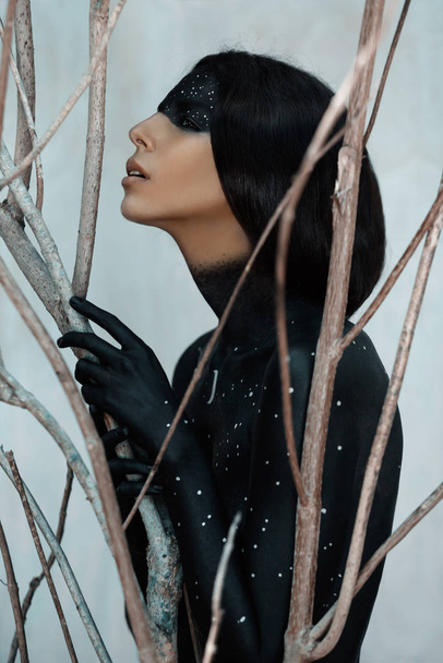 Мистическая женщина в черном боди-арте на фоне веток - Фото, изображение