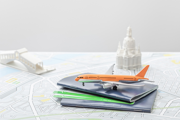 enfoque selectivo de avión de juguete cerca de pasaportes y pequeñas figurillas en el mapa de italia aislado en gris
   - Foto, imagen