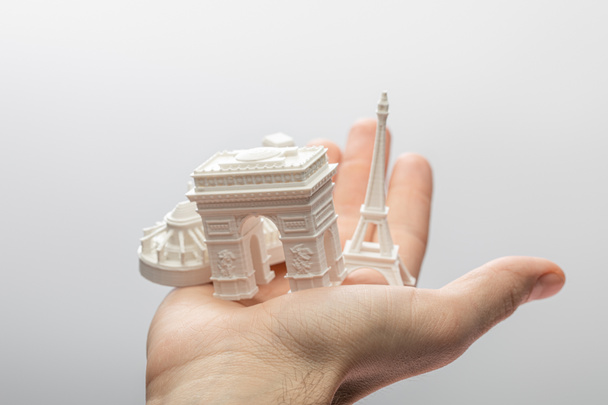 обрезанный вид человека, держащего маленькие сувениры из Парижа изолированные на сером
  - Фото, изображение