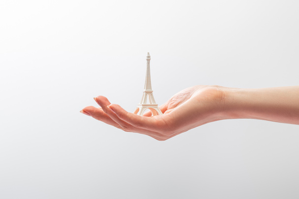 oříznutý pohled na ženu držící malou sošku Eiffelovky izolovanou na bílém  - Fotografie, Obrázek