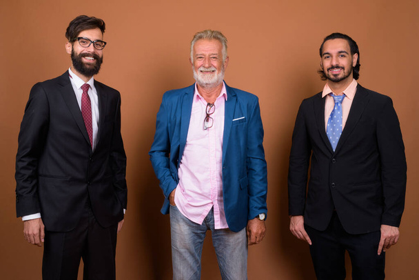 Plan studio de trois hommes d'affaires multi-ethniques barbus ensemble sur fond brun
 - Photo, image