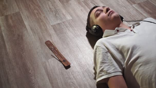 nuori ruskettunut mies lähikuva valkoisessa t-paidassa kotona kuuntelemassa rentouttavaa musiikkia. rentoutuminen rentoutuminen, valon sammuttaminen
 - Materiaali, video
