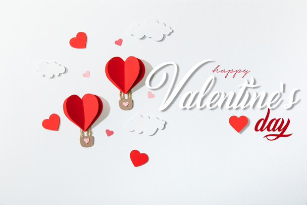 top view of paper heart shaped air balloons in clouds near happy valentines day lettering on white background - Photo, Image