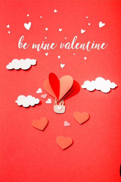 top view of paper heart shaped air balloon in clouds near be mine valentine lettering on red background - Photo, image
