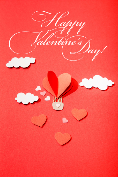 top view of paper heart shaped air balloon in clouds near happy valentines day lettering on red background - Foto, Imagen