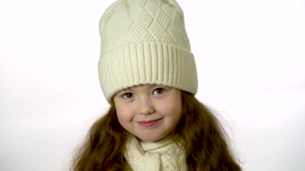 Cute girl 5-6 years old looking at the camera and smiling. Closeup portrait on a white background - Záběry, video