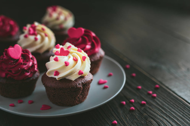 Valentine cupcakes fehér és piros színekben, tálalva a tányéron, és díszített édes szívvel.  - Fotó, kép