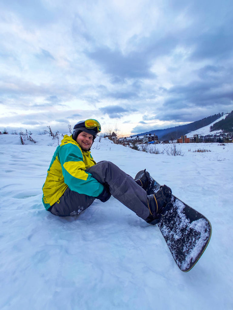 スノーボードをした男が雪山に座って - 写真・画像