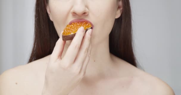 Hermosa hembra comiendo una rebanada de pan artesanal con caviar rojo disfrutando de la toma de sabor en la epopeya roja
 - Imágenes, Vídeo