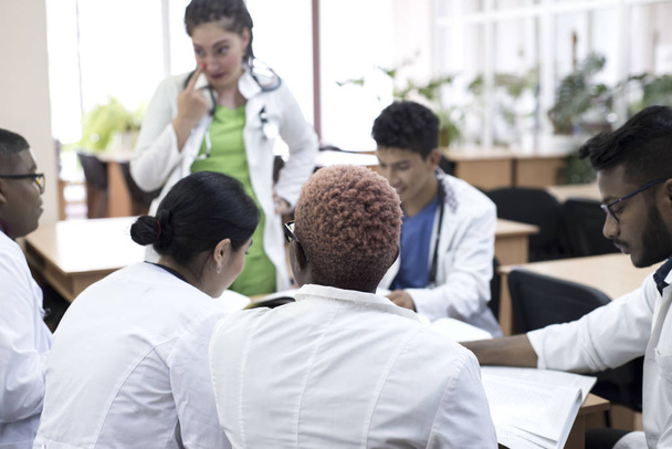 Orvosok egy orvosi konferencián. Egy csapat vegyes bőrű fiatal ül az asztalnál, és hallgatják az előadót.. - Fotó, kép