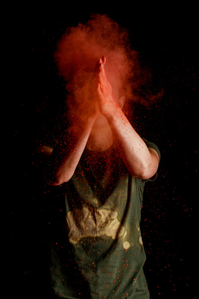 жінка з помаранчевою барвистою фарбою Холі вибух перед обличчям на чорному фоні
 - Фото, зображення