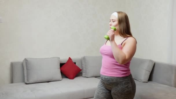 Chubby woman doing exercise by dumbbell in a room - Materiaali, video