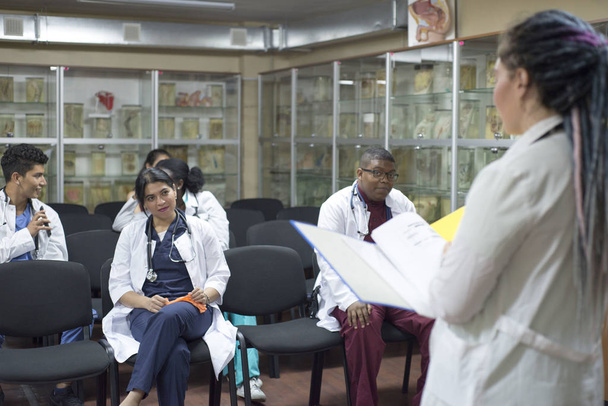 Grupo de trabajadores sanitarios con tableta digital reunidos en la sala de juntas del hospital. Personal médico durante la sesión informativa matutina
. - Foto, imagen