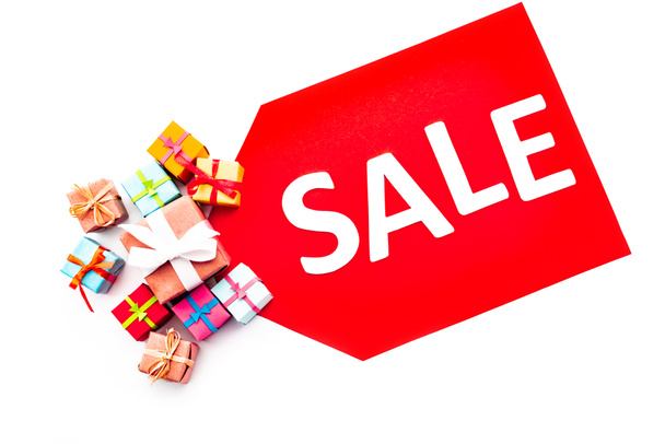 Beyaz üzerine izole edilmiş hediyelerin yanında satılık harflerle kırmızı fiyat etiketinin üst görünümü - Fotoğraf, Görsel