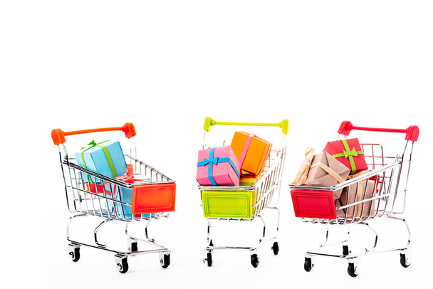 pequeños carritos de compras decorativos con cajas de regalo aisladas en blanco
 - Foto, imagen