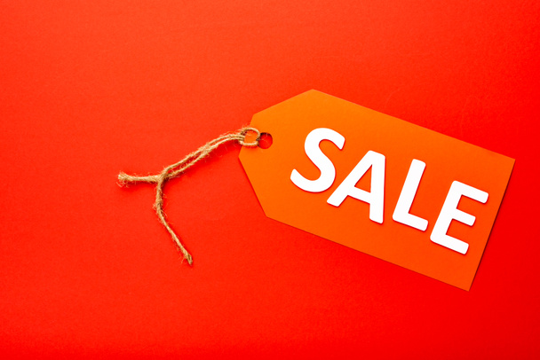 top view of price tag with sale lettering isolated on red - Foto, Imagem