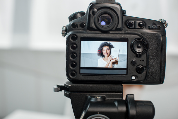 selectieve focus van digitale camera met Afrikaanse Amerikaanse video blogger met notebook met influencer marketing belettering op het display  - Foto, afbeelding