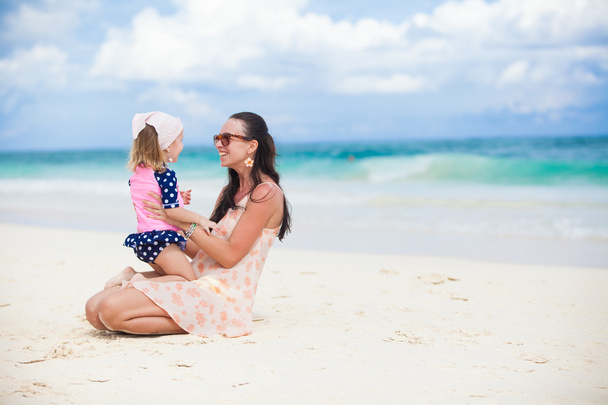 若い母親と彼女の小さな娘は熱帯のビーチで楽しい時を過す - 写真・画像