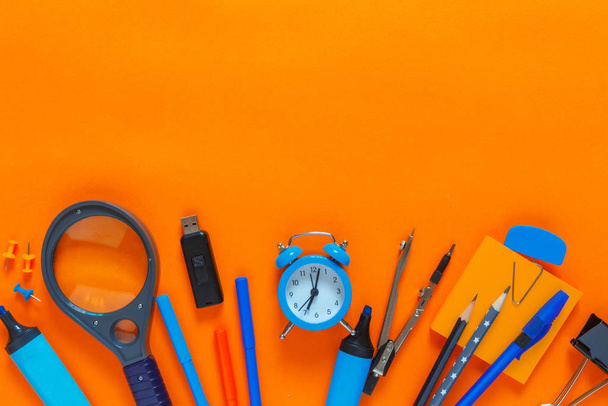 Back to school. Flat lay creative set of school supplies, notebook, pens, markers, alarm clock, compass. School background orange color - Photo, image