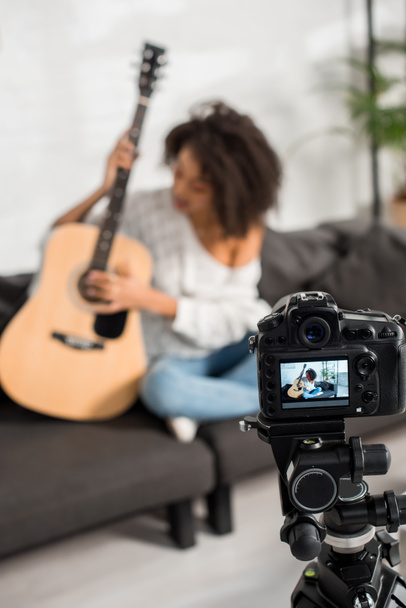Selektive Fokussierung der Digitalkamera mit einem jungen afrikanisch-amerikanischen Mädchen auf der Akustikgitarre  - Foto, Bild