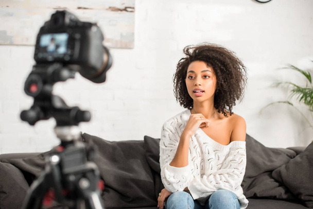 szelektív fókusz a fiatal és göndör afro-amerikai lány fogszabályzó beszél közelében digitális fényképezőgép  - Fotó, kép