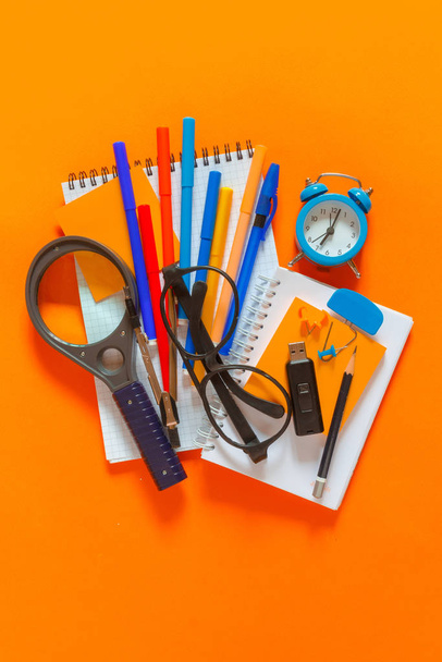 De vuelta a la escuela. Set creativo plano de útiles escolares, cuaderno, bolígrafos, marcadores, despertador, brújula. Fondo escolar color naranja
 - Foto, Imagen