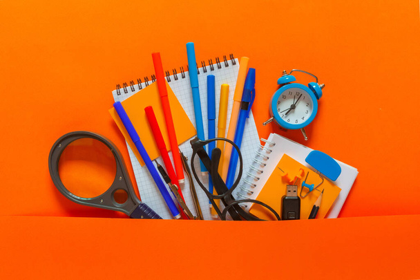 Creative flat top view of the position of school supplies stationery, education elements on an orange background. Concept back to school template for your text or design. - Photo, image
