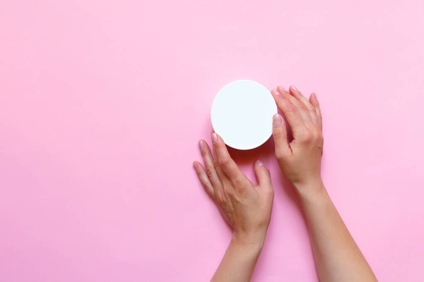 Woman's hands moisturizing cosmetic cream, lotion on a pink background with copy space, beauty, care concept. Pattern flat lay top view - Photo, Image