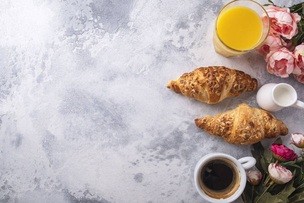 Sabroso desayuno con café, zumo y cruasanes frescos sobre un fondo gris. Vista superior
 - Foto, imagen