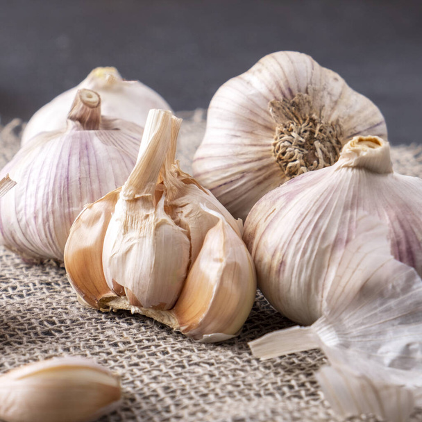Garlic cloves and bulb on burlap background. Closeup - Photo, Image