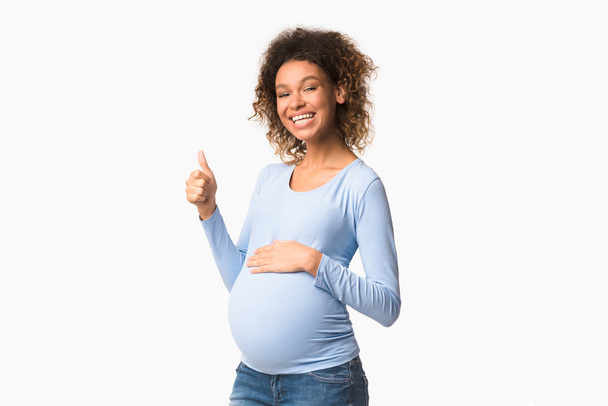 Gelukkige zwangerschap. Positieve zwarte zwangere vrouw gebaren duim omhoog - Foto, afbeelding