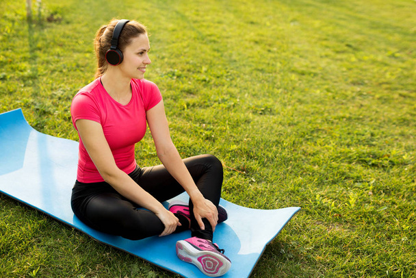  beautiful young woman in sportswear is training in the summer in the park - Фото, изображение