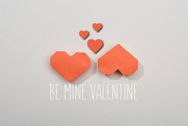 Top view of two red paper hearts on grey background with be mine valentine lettering - Foto, imagen