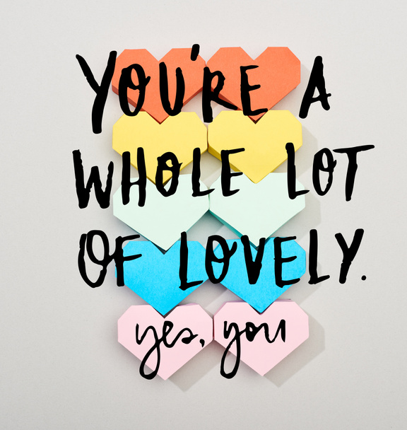 Top view of colorful heart shaped papers on grey background with you are a whole lot of lovely lettering - Foto, immagini