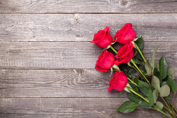 Red roses flowers on gray wooden table. Valentine's greeting card. Top view. Copy space - 写真・画像