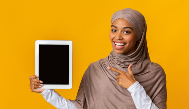 Czarny Muzułmanin kobieta wskazując na cyfrowy tablet z czarnym ekranem - Zdjęcie, obraz