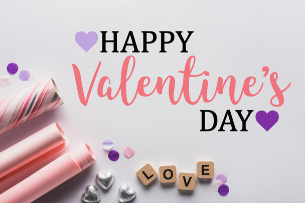 top view of silver hearts, wrapping paper and cubes with love lettering on white background with happy valentines day illustration - Valokuva, kuva
