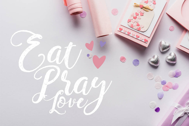 top view of valentines decoration, gifts, hearts and wrapping paper on white background with eat, pray, love lettering - Photo, image