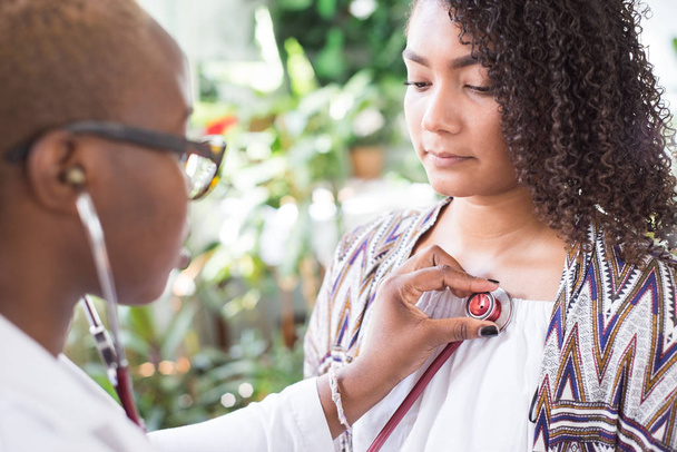 African American girl doctor using a stethoscope to conduct auscultation for a patient. Mixed Race Youth - Foto, imagen