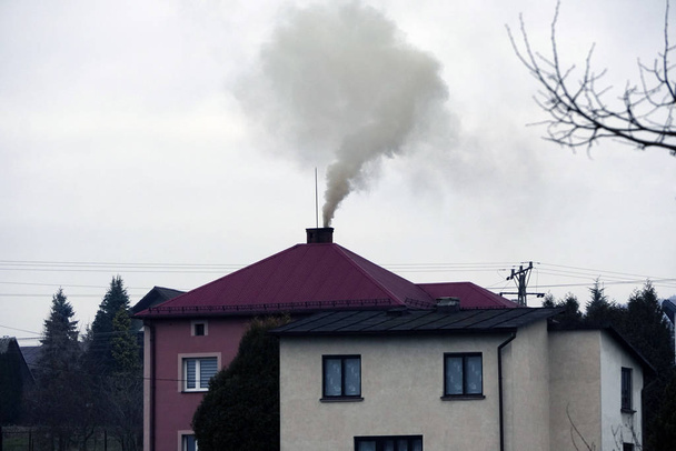 il fumo nero viene da camino di una casa contro cielo grigio, calore
 - Foto, immagini