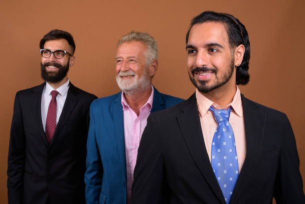 Три багатонаціональні бородаті бізнесмени разом на коричневому тлі
 - Фото, зображення