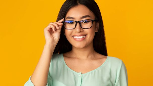 Optical shop. Happy asian girl in glasses looking at camera - Photo, Image