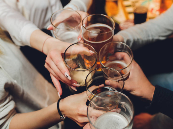 Nahaufnahme einer Gruppe von Menschen, die vor Bokeh-Hintergrund Gläser mit Wein oder Champagner klappern. Ältere Hände. - Foto, Bild